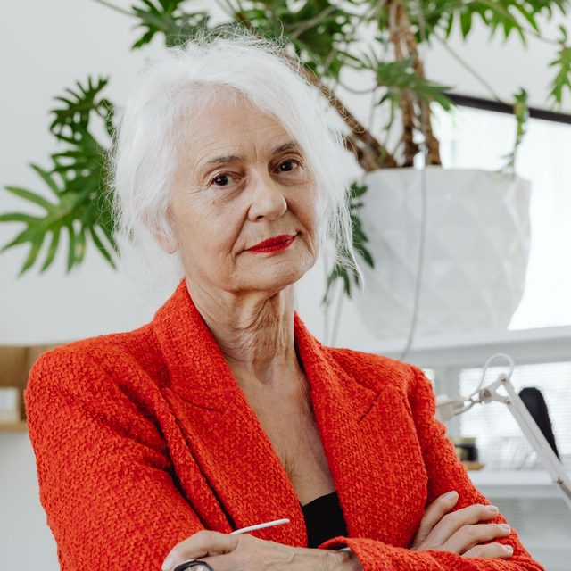 Femme senior aux cheveux blancs en veste rouge, bras croisés