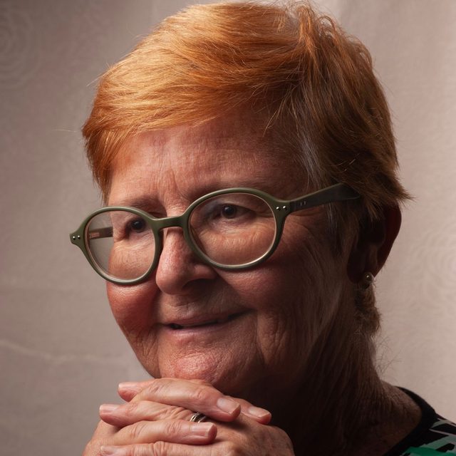 Femme senior aux cheveux roux et lunettes, mains jointes