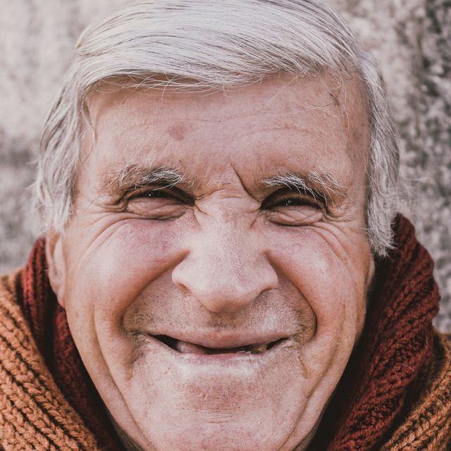 Homme senior riant franchement, écharpe, plein air