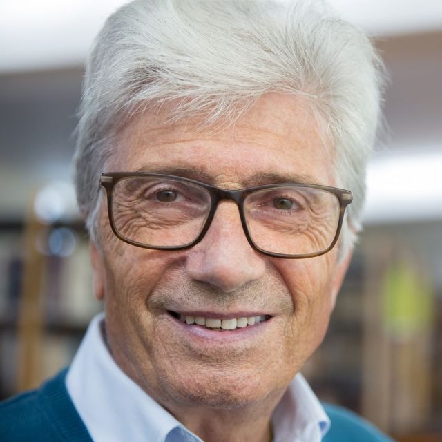 Homme senior à lunettes en veste bleue, fond neutre
