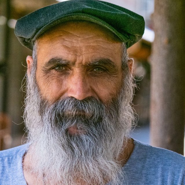 Homme senior en casquette verte, barbe grise fournie